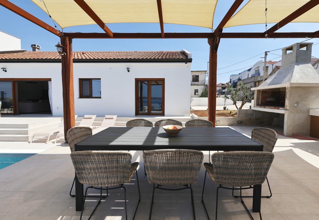 Terrace dining area of Villa Diaria with pergola, barbecue area and pool in Vrsi