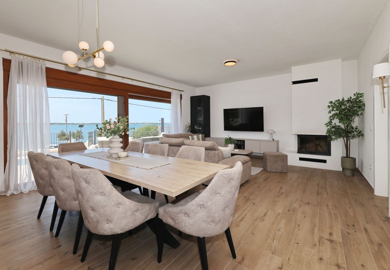 Open living and dining area of Villa Diaria with dining table, fireplace and sea view in Vrsi