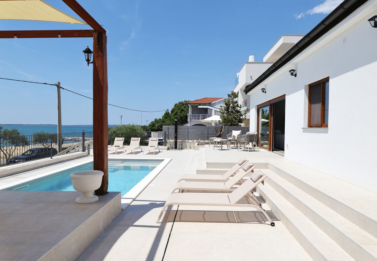 Pool terrace of Villa Diaria with sun loungers, house access and side sea view in Vrsi