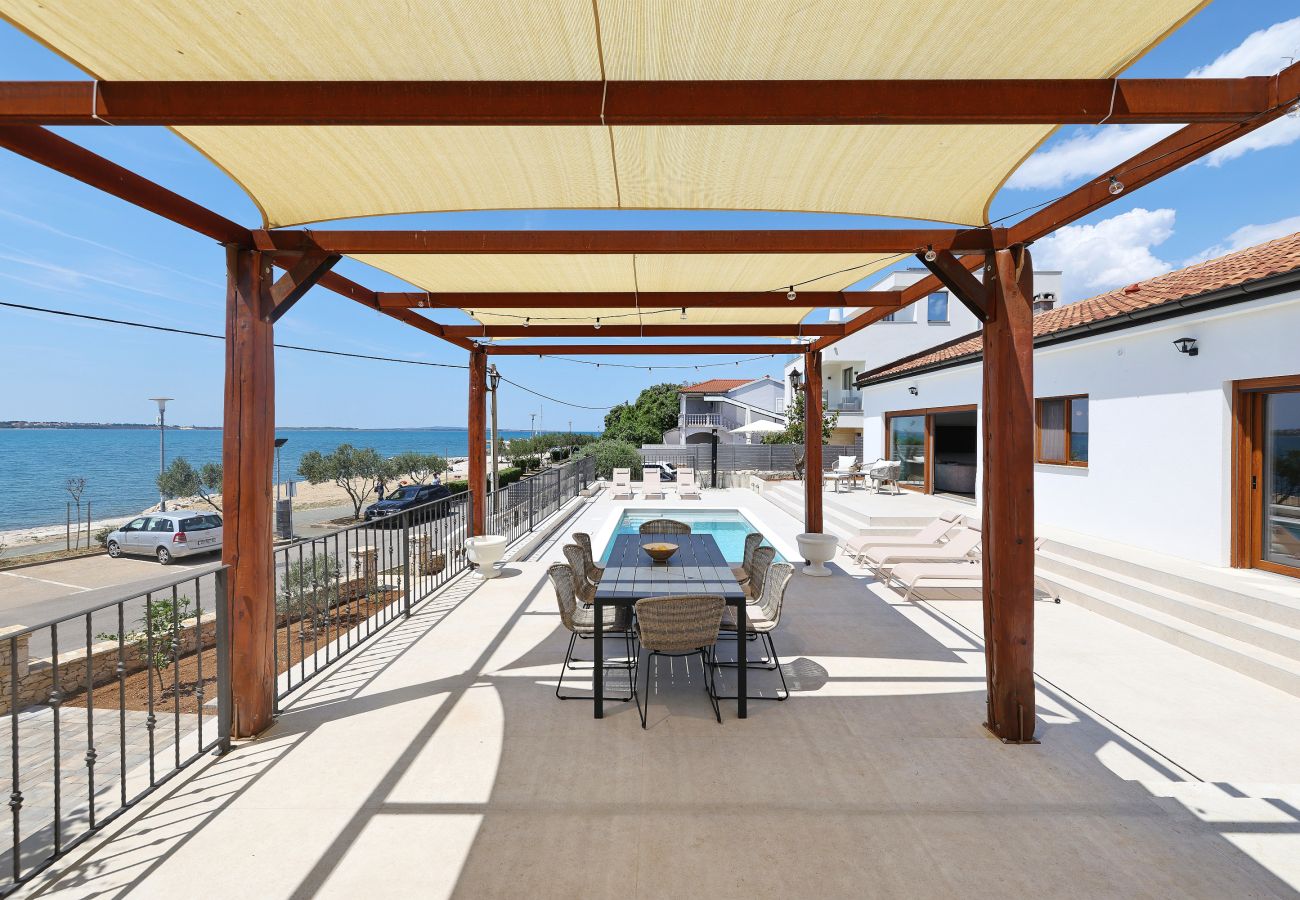 Covered terrace of Villa Diaria with dining area, pool area and sea view in Vrsi