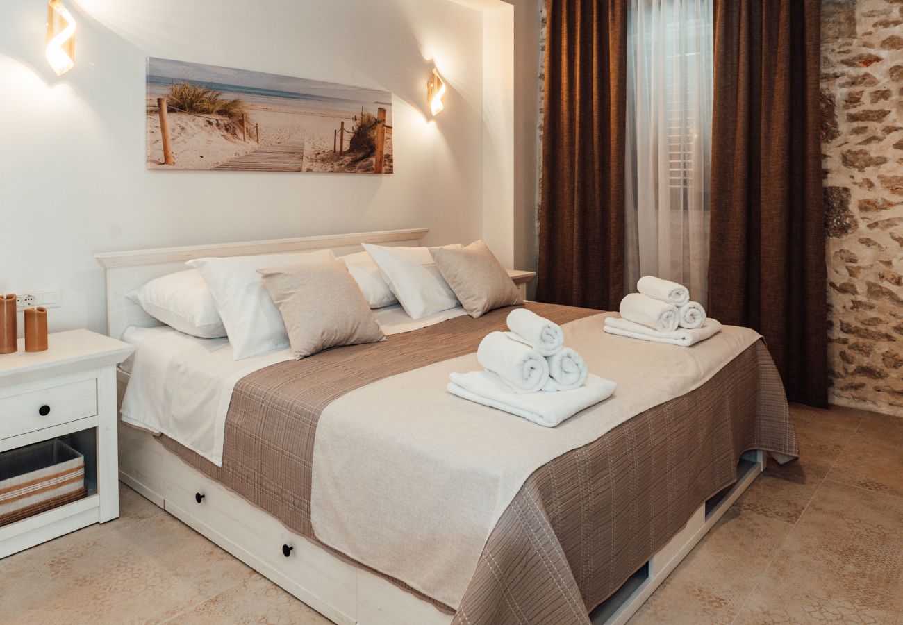 Ground-floor bedroom of Gland Residence in Nin with king-size double bed, air conditioning and stone details.