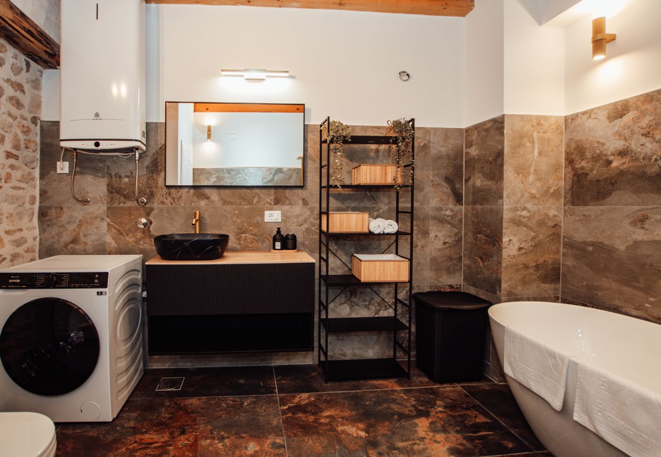 Ground-floor bathroom of Gland Residence in Nin with bathtub, washbasin, washing machine and modern fittings.