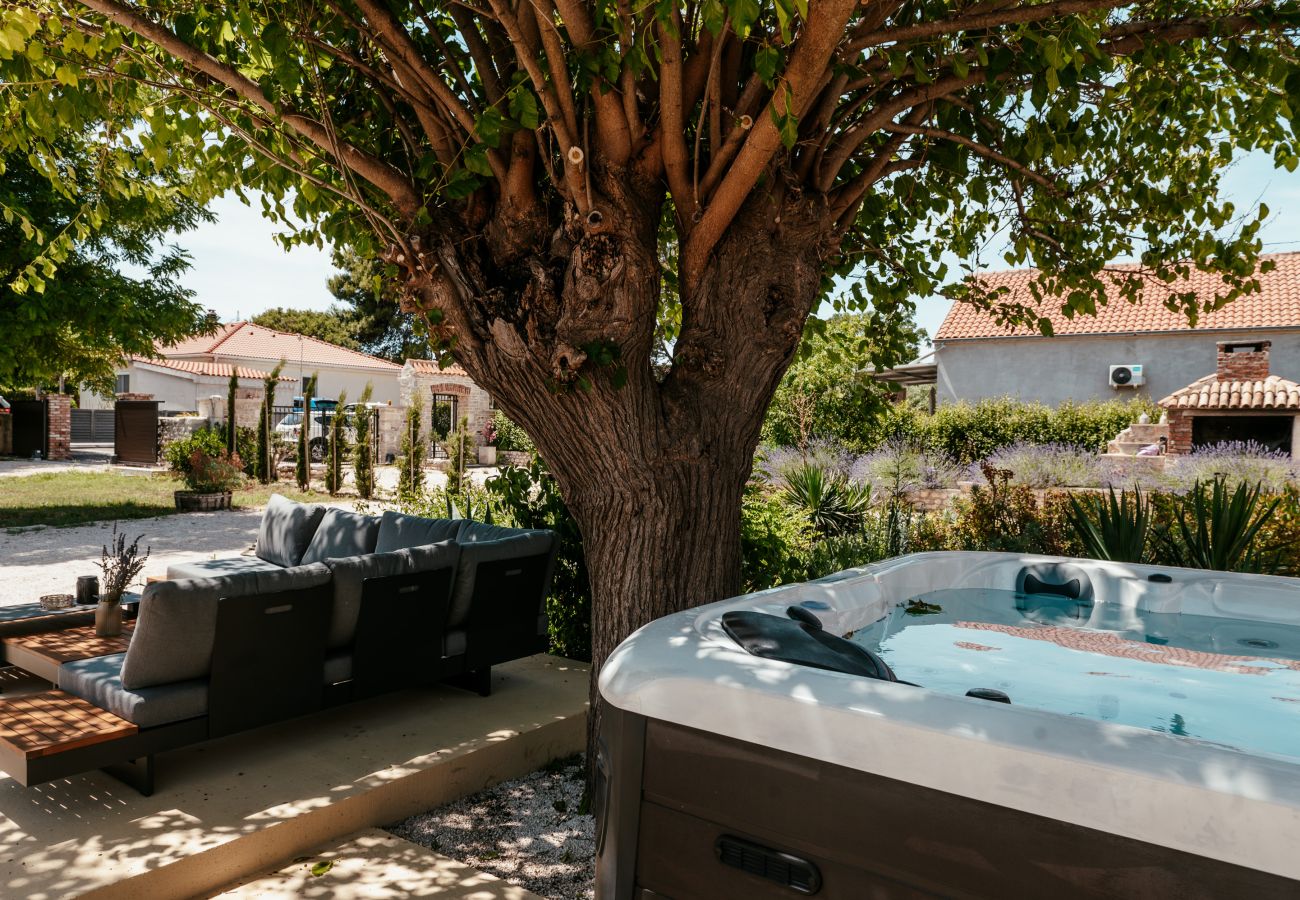 Shaded garden area of Gland Residence in Nin with private whirlpool, lounge and large tree.