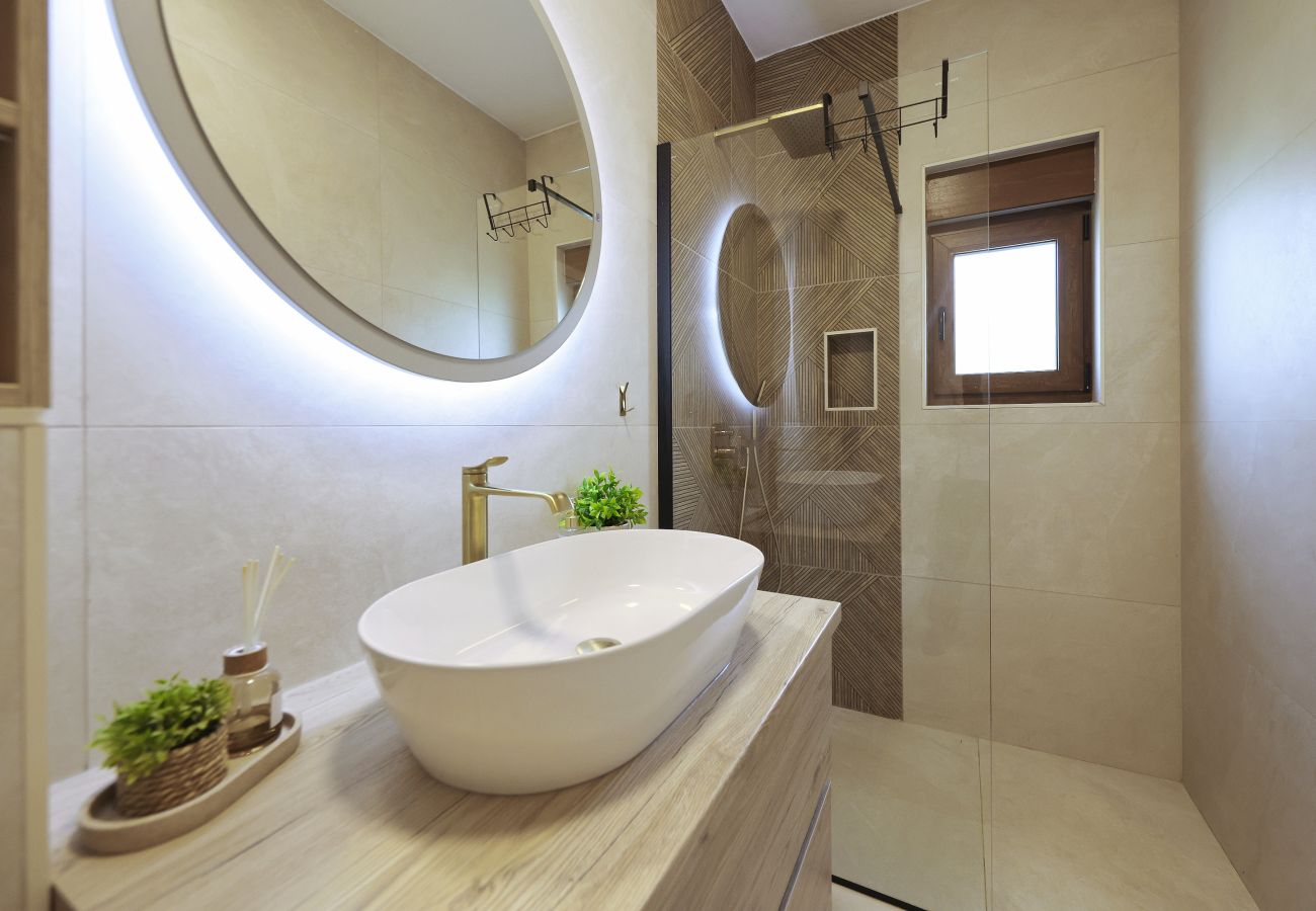 Modernes Badezimmer der Villa Diaria mit Waschtisch, beleuchtetem Spiegel und bodengleicher Dusche in Vrsi