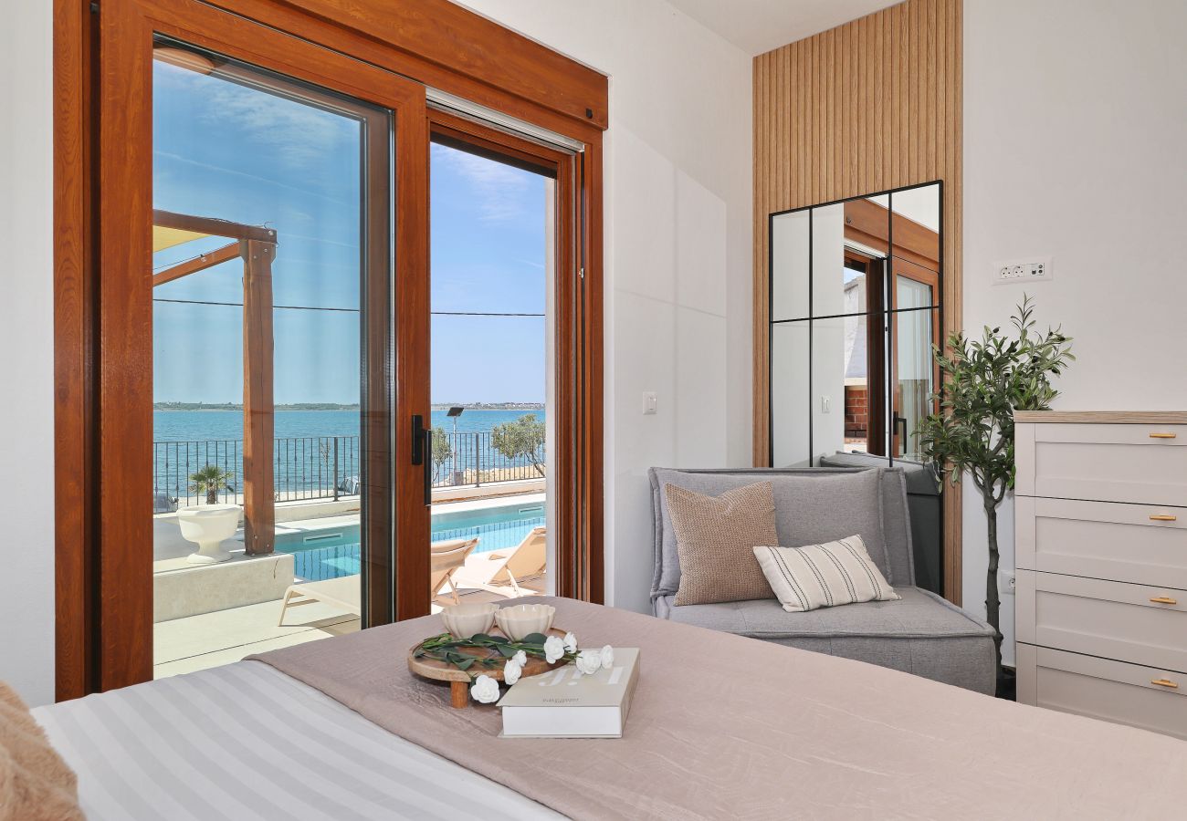 Schlafzimmer der Villa Diaria mit Bett, Sitzbereich, Terrassenzugang, Poolblick und Meerblick in Vrsi