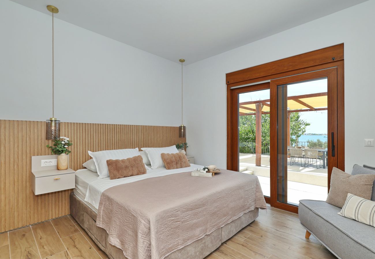 Schlafzimmer der Villa Diaria mit Kingsize-Bett, Sitzbereich, Terrassenzugang und Meerblick in Vrsi