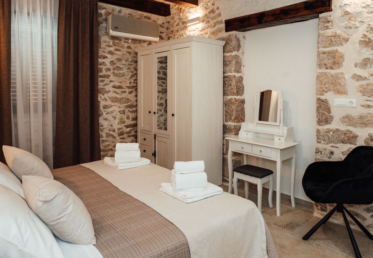 Schlafzimmer im Erdgeschoss der Gland Residence in Nin mit Klimaanlage, Kleiderschrank, Schminktisch und Natursteinwand.