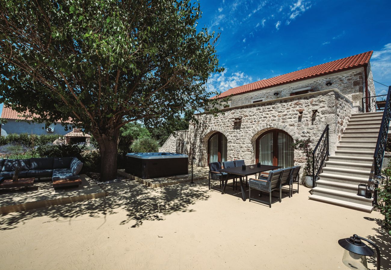 Gartenbereich der Gland Residence in Nin mit Natursteinfassade, privatem Whirlpool, Lounge und Essplatz