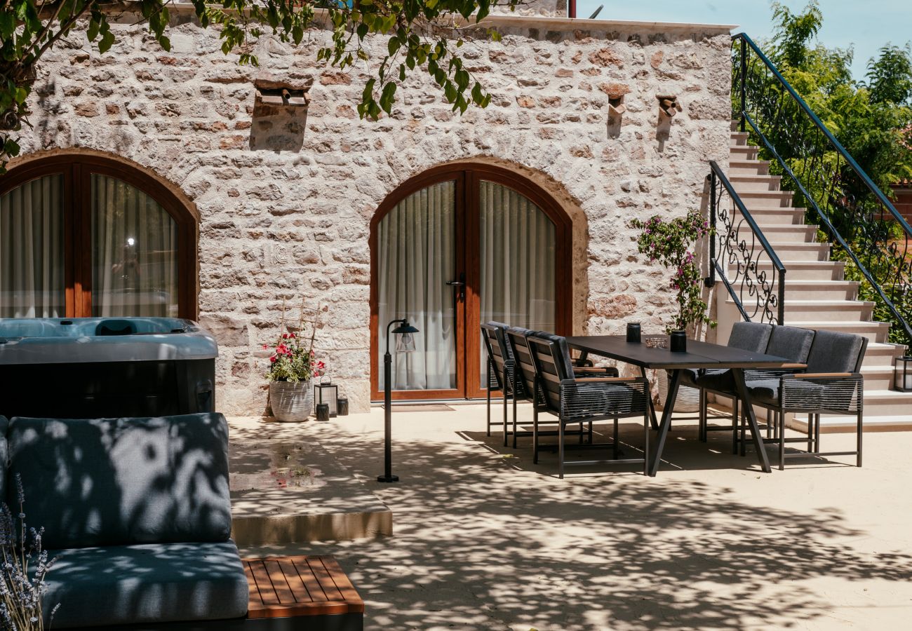 Terrasse der Gland Residence in Nin mit Essplatz im Freien, privatem Whirlpool, Natursteinfassade und Außentreppe.